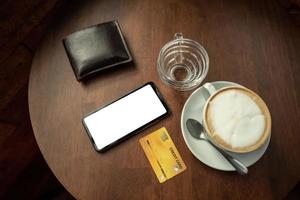 Credit cards and telephone are placed on a wooden table at the coffee shop. photo