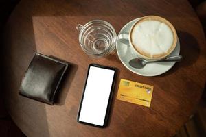 Credit cards and telephone are placed on a wooden table at the coffee shop. photo