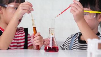 los niños están aprendiendo y haciendo experimentos científicos en el salón de clases. dos hermanitas jugando al experimento científico para la educación en el hogar. Experimentos científicos fáciles y divertidos para niños en casa. video