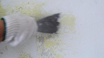 gros plan sur une main de travailleur grattant la vieille peinture sur un mur en béton avec une spatule en métal. rénovation et peinture des murs de la maison. préparation pour peindre une pièce video