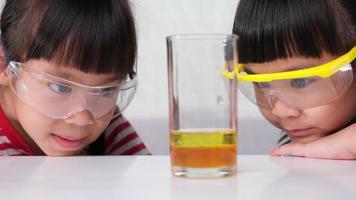 los niños están aprendiendo y haciendo experimentos científicos en el salón de clases. dos hermanitas jugando al experimento científico para la educación en el hogar. Experimentos científicos fáciles y divertidos para niños en casa. video