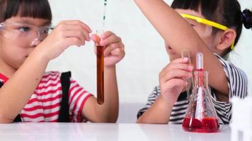 los niños están aprendiendo y haciendo experimentos científicos en el salón de clases. dos hermanitas jugando al experimento científico para la educación en el hogar. Experimentos científicos fáciles y divertidos para niños en casa. video