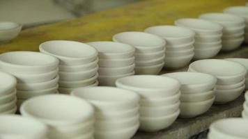 muchos pequeños platos redondos hechos de arcilla cerámica. taza de cerámica en el estante para preparar el diseño de pintura en la superficie en el taller de cerámica. artesanía y concepto de pequeña empresa. video