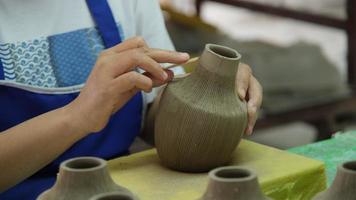 close-up da mão de uma mulher fazendo padrões em um vaso de barro em uma oficina de cerâmica. processo de fabricação de um vaso de cerâmica. artesanato e conceito de empresa de pequeno porte.
