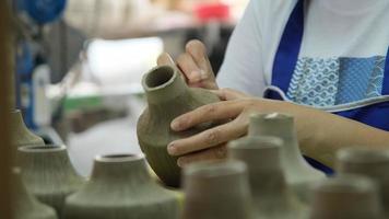 närbild av en kvinnas hand gör mönster på en lervas i en keramikverkstad. processen att göra en keramisk vas. hantverk och små affärsidé. video
