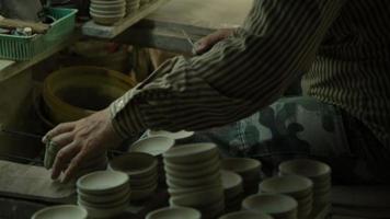 mão feminina segurando um pincel para pintar produtos de barro, close-up. o processo de pintar à mão uma tigela de cerâmica feita à mão.