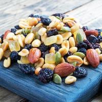 A mixture of nuts and dried fruits on a wooden chopping board, rustic background. Concept of healthy food. photo