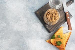 Homemade chicken liver pate in a glass jar on a gray concrete table. Copy space. photo
