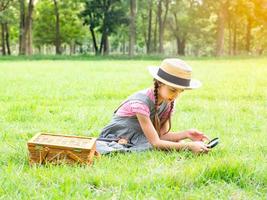 The girl sits on the grass, using a magnifying glass to look at the flowers in the field photo