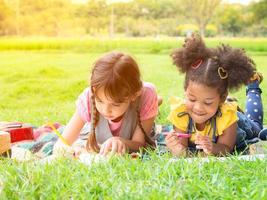 un grupo de niños pequeños de muchas nacionalidades juegan y aprenden fuera de la escuela foto