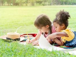 un grupo de niños pequeños de muchas nacionalidades juegan y aprenden fuera de la escuela foto