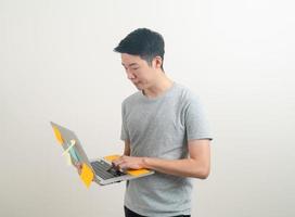 young Asian man holding laptop with stress face or working hard photo