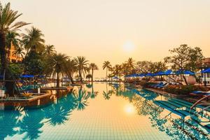 Palmera con sombrilla piscina en hotel resort de lujo al amanecer. foto