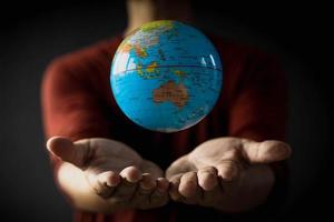 Close-up of a globe floating above a man's hand on a blurred background. Earth day concept with low key tone photo