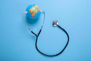 Creative flat lay composition of globe and stethoscope on pastel blue background with copy space photo