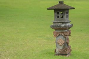 Decorative traditonal lamp from stones, lantern in green grass. Garden design. photo