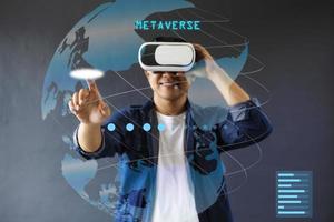 Smiling man is use VR googles and touch hologram screen againts dark grey background. photo