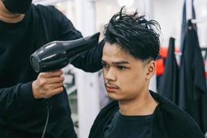 Young man visiting barbershop. Hairdresser drying consumer's hair. Self-care, masculine beauty. Barber. Modern hair style photo