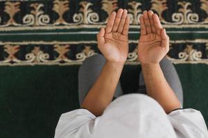 vista superior de la mano de un hombre musulmán rezando a Alá en la mezquita foto