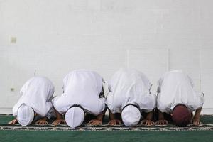 A group of Muslims are praying with prostrating movements in the mosque photo