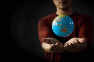 Close-up of a globe floating above a man's hand on a blurred background. Earth day concept with low key tone photo