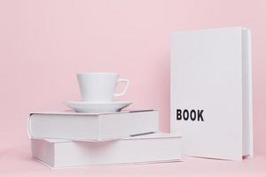 combinación de taza y libro para maqueta aislado sobre fondo rosa foto