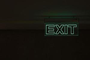 Green Exit Sign Isolated In Dark Black Room photo