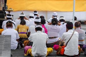 Back view of Balinese people with traditional clothes praying together photo