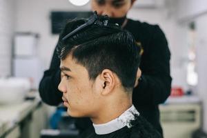 Side view of young male consumer being shaved at the salon photo