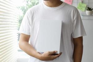 Cropped man holding book on chest for book mock up photo