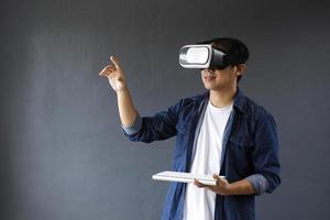 hombre sonriente usando gafas de realidad virtual y teclado inalámbrico, disfruta de los juegos como si tocara o hiciera clic en la pantalla digital. copie el espacio para el concepto futurista de negocios, educación y juegos. foto