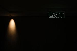 Green exit sign isolated in dark black room with little yellow  spotlight photo