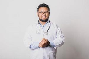 Casual male doctor posing with his palms together isolated on white background photo