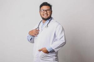 Stylish happy male doctor with hands in pockets isolated on white background photo