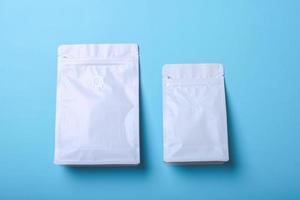 White standing pouch bag with zip lock and valve on blue background, mock up for coffee packaging. Top view. Can be use for template your design, presentation, promo, ad. photo