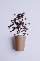 Paper cup and coffee beans isolated on white background. Packaging mock up for coffee product. photo