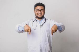 Cheerful male doctor pointing with both hands down isolated on white background photo