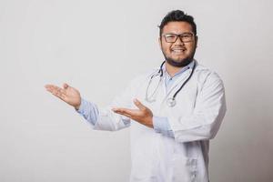 Cheerful male doctor presenting sideways isolated on white background with copy space photo