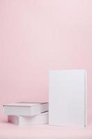 Plain white book with stack of books isolated on pink background for Book mock up photo