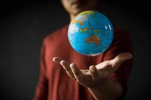 Close-up of a globe floating above a man's hand on a blurred background. Earth day concept with low key tone photo