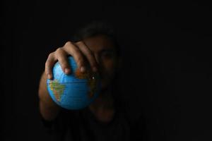 Hand holding globe on black background with copy space. Earth day concept with low key tone photo