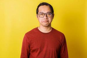 Casual man in glasses with disappointed facial expression isolated on yellow background photo