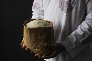 Muslim hand holding alms bag of rice isolated on black background photo
