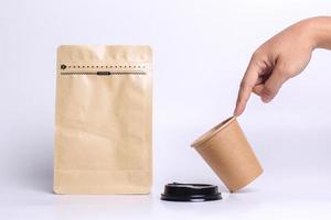 Index finger pointing out paper cup and standing pouch bag with zip lock isolated on white background. Realistic set mock up for branding,  template for your design, presentation, promo, ad. photo