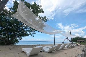 Perspective line of  sunbeds under the dramatic blue sky at beachfront, sea side. photo