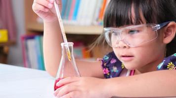 kinderen leren en doen wetenschappelijke experimenten in de klas. klein meisje dat wetenschappelijk experiment speelt voor thuisonderwijs. eenvoudige en leuke wetenschappelijke experimenten voor kinderen thuis. video