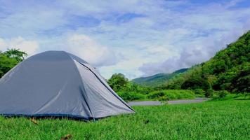 lasso di tempo di uno scenario naturale di foreste tropicali con montagne e fiumi che scorrono con tenda da campeggio sul prato in una luminosa giornata estiva. video