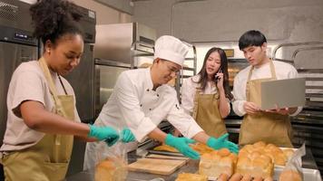 A chef's team staff who make bread dough and pastry foods are busy with homemade baking jobs while cooking orders online, packing, and delivering on bakery shop business, small business entrepreneur. video