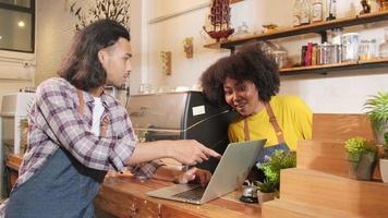 Two cafe business startup partners and friends, African American female, and Thai male baristas talk and cheerful smile together at counter bar of coffee shop, happy service job, and SME entrepreneur. video