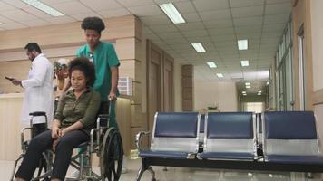 Young African American female doctor with stethoscope in uniform checks injury patient girl in wheelchair at outpatient accident clinic hospital, illness medical clinic examination, healthcare hall. video